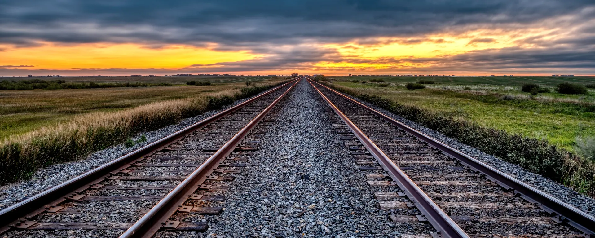Railway tracks stretching towards a sunset